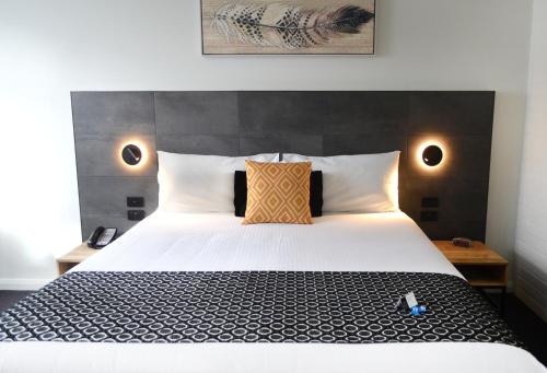 a bedroom with a large white bed with two pillows at Orana Motel in Dubbo
