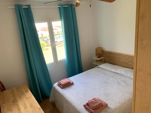 um quarto com uma cama com cortinas azuis e uma janela em Ca la Marta apartamento con piscina y jardín a 150m de la playa em Arenal d'en Castell