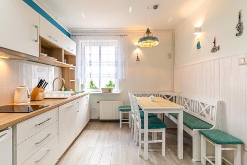 a kitchen with a table and a dining room at Apartament NaFali in Niechorze