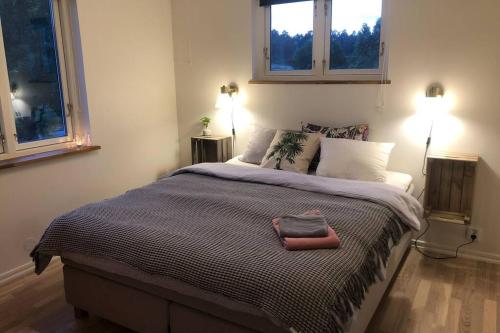 a bedroom with a large bed with two windows at Cottage perfect for short time rent in Gustavsberg
