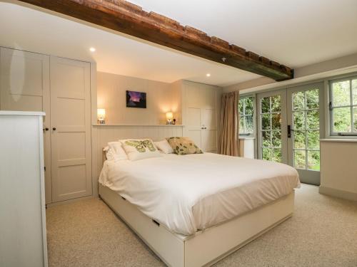 a bedroom with a large white bed and windows at Hillside Cottage in Shaftesbury