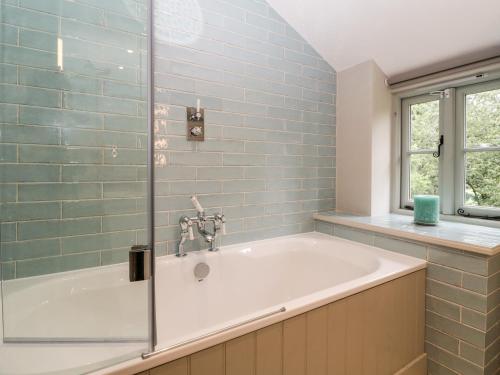 a bath tub in a bathroom with blue tiles at Hillside Cottage in Shaftesbury