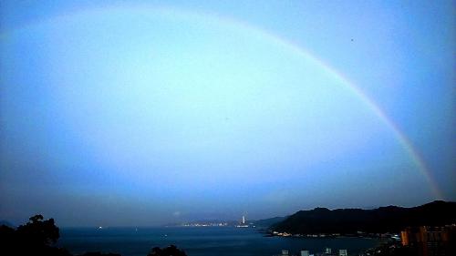 a rainbow in the sky over the water with a city at Villa High Wharf in Wanli District