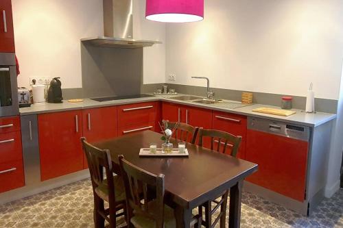 una cocina con armarios rojos y una mesa con sillas. en obouduchemin, en Cindré