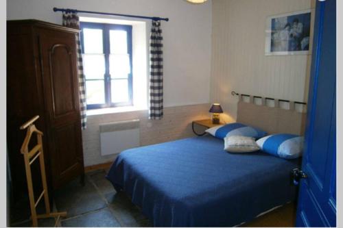 Schlafzimmer mit einem Bett mit blauer Bettwäsche und einem Fenster in der Unterkunft obouduchemin in Cindré