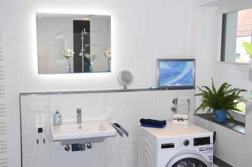 een badkamer met een wasmachine en een wastafel bij Top-Moderne und geräumige Ferienwohnung in Aßling