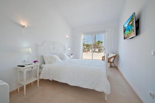 a white bedroom with a white bed and a window at Villa Mar in Alcudia