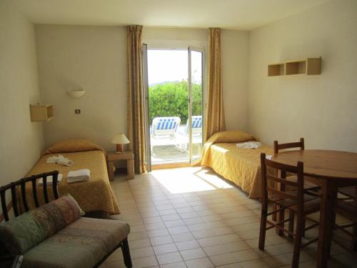 Habitación de hotel con 2 camas, mesa y patio en Motel Saint Francois, en Calvi