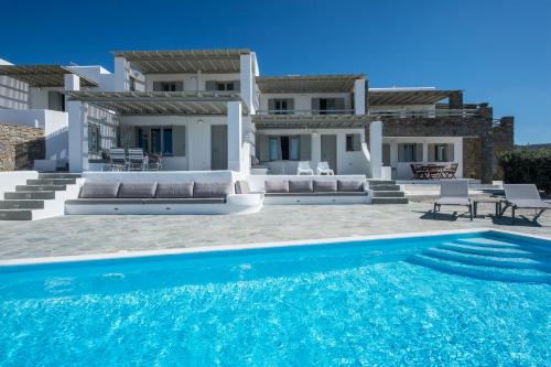 a villa with a swimming pool in front of a house at Anemos in Parikia