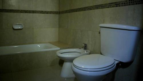 a bathroom with a white toilet and a bath tub at Cabañas Amalar in Malargüe