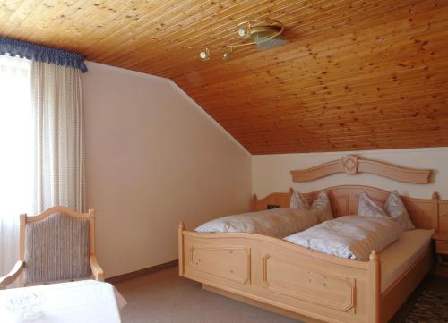 Schlafzimmer mit einem Bett mit Holzdecke in der Unterkunft Erd´s Hoimatle Ferienwohnung in Jungholz