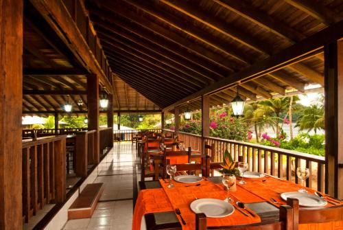 un restaurante con mesas de madera y sillas en el balcón en Playa de Oro Lodge, en Bahía Solano