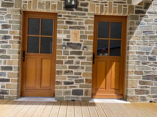 two wooden doors on a stone building with a man in the window at The Splendid View - 8 Personnes in Bouillon