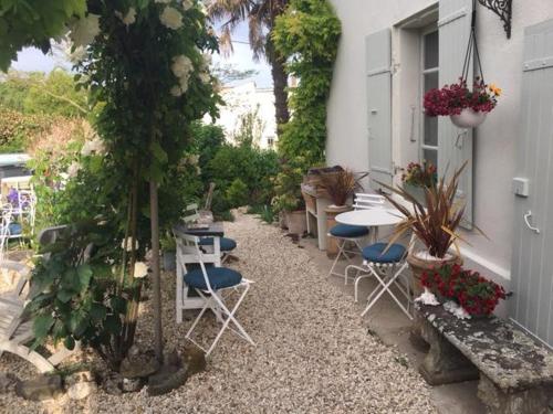a garden area with a table, chairs, and plants at Chez Brown in Saint-Thomas-de-Cônac