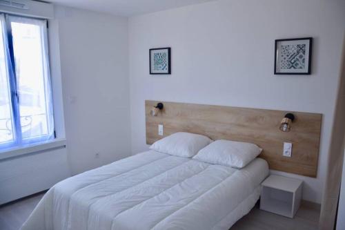 a bedroom with a white bed with a wooden headboard at Les Forges studio étage in Avoine