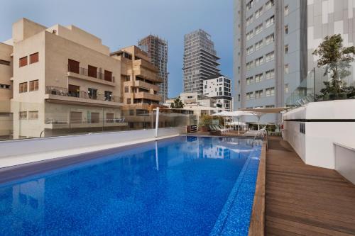 a large swimming pool in a city with buildings at Metropolitan Hotel in Tel Aviv