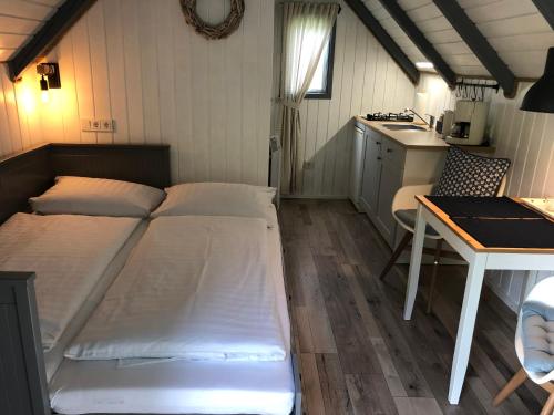 ein Schlafzimmer mit Bett und Tisch und eine Küche in der Unterkunft Ferienhaus Vogelkoje in Emmelsbüll-Horsbüll