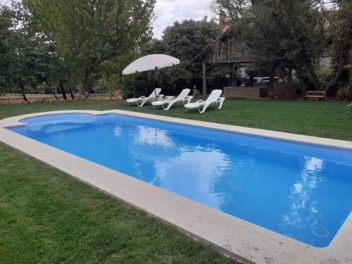 ein blauer Pool mit Stühlen und einem Sonnenschirm in der Unterkunft O cuco de Mondariz in Mondariz