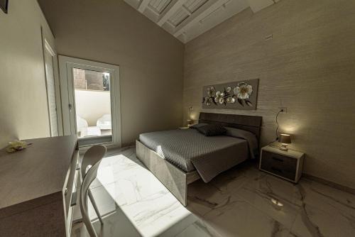 a bedroom with a bed and a table and a window at Corleone GUESTHOUSE in Corleone