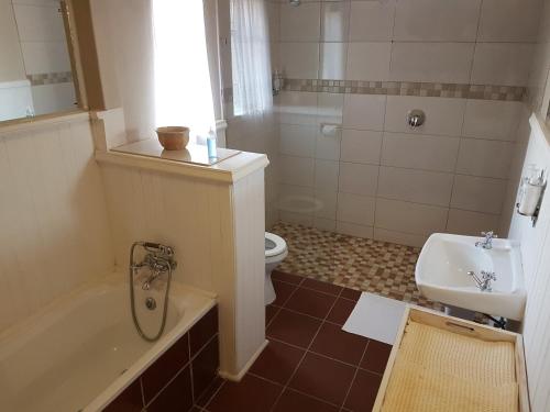 a bathroom with a tub and a toilet and a sink at Crane Cottage in Colesberg