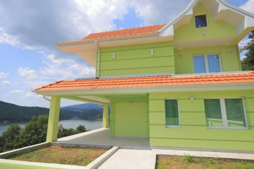 a green house with a view of the water at Bovan GREEN LAKE apartments in Soko Banja