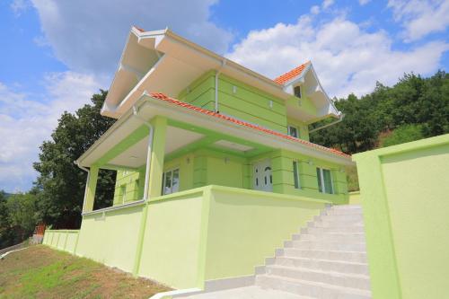 a yellow and green house with stairs in front of it at Bovan GREEN LAKE apartments in Soko Banja