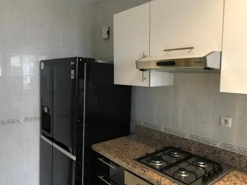 Il comprend une cuisine équipée d'un réfrigérateur noir et de placards blancs. dans l'établissement appartement 69 vue sur mer 3 chambre, à Tanger