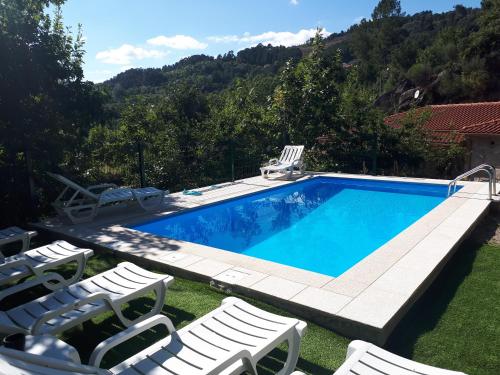 a swimming pool with lounge chairs and a swimming poolvisor at Casa da Fragoeira in Gandarela