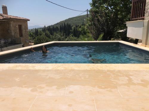 a woman swimming in a swimming pool in a house at Villagio inn Suite & Spa in Soúlion