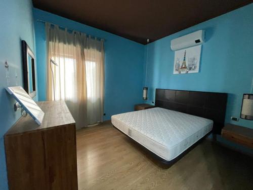 een slaapkamer met een bed en een blauwe muur bij Casa Mana in Scalea