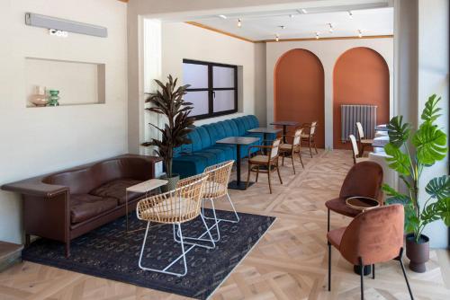 a waiting room with a couch and tables and chairs at Nest in Győr