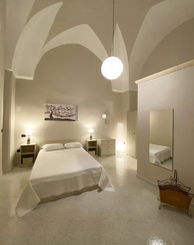 a white bedroom with a large bed and a mirror at A Casa di Nonna Ada in Manduria