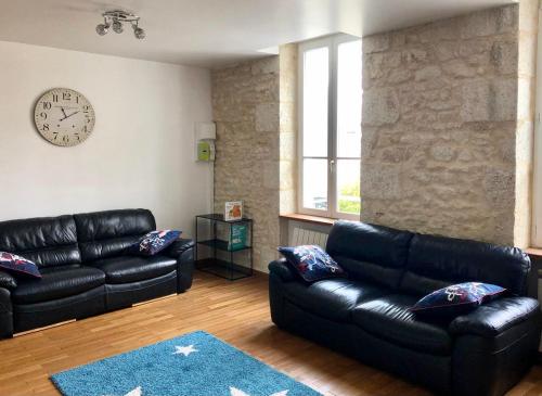 a living room with black leather couches and a clock at Cœur de la Charité sur Loire in La Charité-sur-Loire