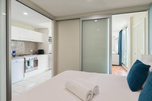 a bedroom with a white bed with blue pillows at Beachside Luxury Apartments One & Two Bedroom in Beachfront Oaks Pier Building in Glenelg