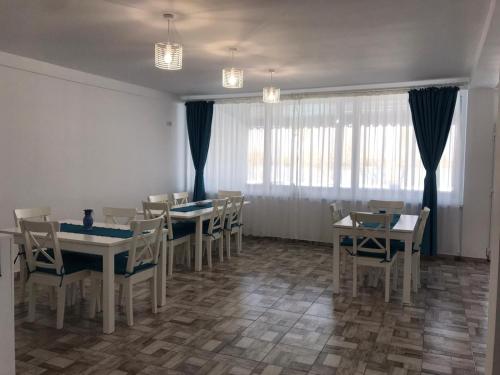 a dining room with tables and chairs and windows at Pensiunea Rares in Creţeşti