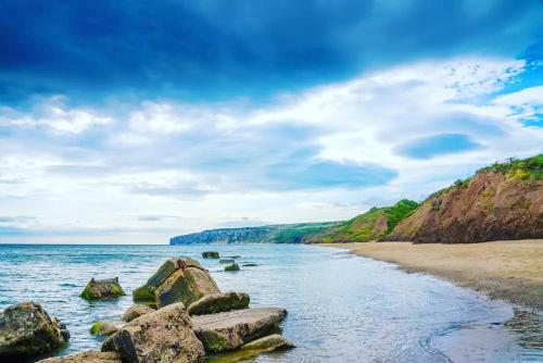 a beach with some rocks in the water at Bay Retreat Apartment The Bay Holiday Village Filey Homesweetholidayhomes in Filey