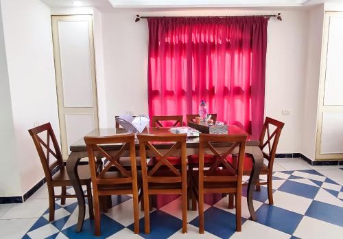 a dining room table with chairs and a red curtain at Zafero beach FAMILIES ONLY in Alexandria