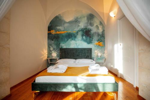 a bedroom with a bed with a painting on the wall at Hostunia in Ostuni