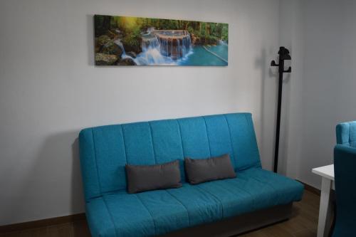 a blue couch in a room with a painting on the wall at APARTAMENTO EL ROMERAL in Alhaurín de la Torre