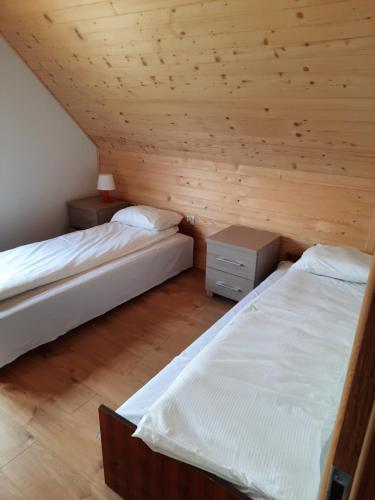 two beds in a room with wooden walls at Leśny Zakątek Radocza in Radocza