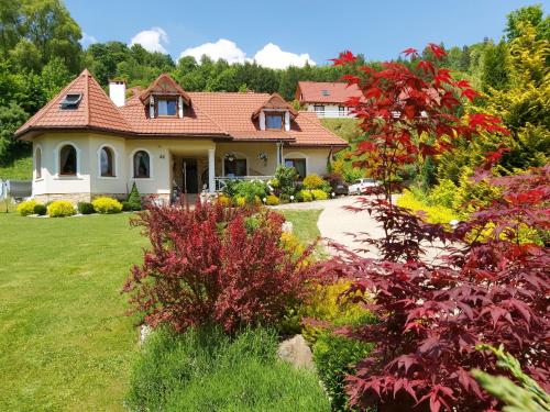 a house with a garden in front of it at Domki nad Cichym Dworkiem in Polańczyk