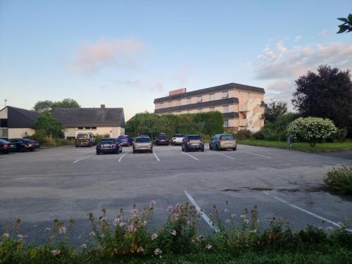 a parking lot with cars parked in front of a building at Hotel du Haut Marais in Saint-Marcel