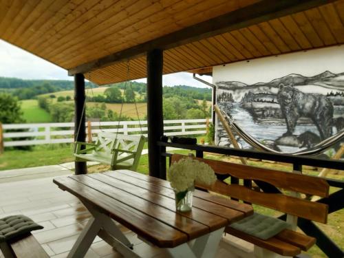 a wooden table and bench on a porch with a mural at Osada wspomnień in Polańczyk