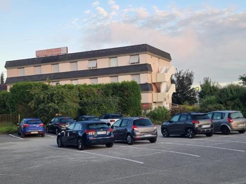 a parking lot with cars parked in front of a building at Hotel du Haut Marais in Saint-Marcel