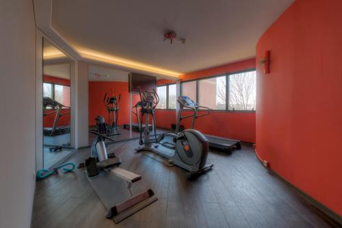 - une salle de sport avec des équipements de cardio-training dans une salle aux murs orange dans l'établissement Best Western Plus Metz Technopole, à Metz