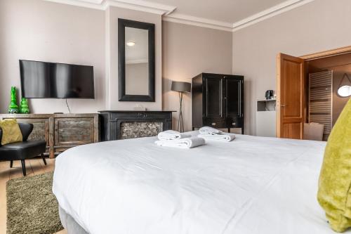 a bedroom with a large white bed and a television at House of Bruges in Bruges