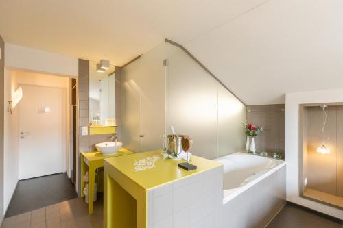 a bathroom with a yellow counter and a sink and a tub at Hotel Restaurant Sternen in Gelfingen