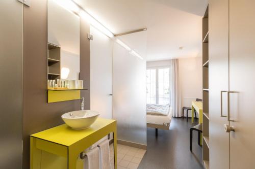 a bathroom with a yellow sink and a mirror at Hotel Restaurant Sternen in Gelfingen