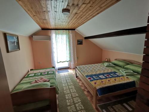 2 Einzelbetten in einem Zimmer mit Fenster in der Unterkunft Apartman Jaredić - Private Accommodation, Privatni Smeštaj in Donji Milanovac
