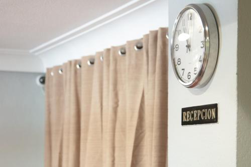 une horloge suspendue sur un mur à côté d'un rideau dans l'établissement Hotel Los Kekes, à Coria